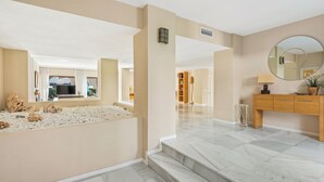 A modern interior with a marble floor, beige walls, a wooden cabinet with a mirror, and a small indoor garden with rocks.