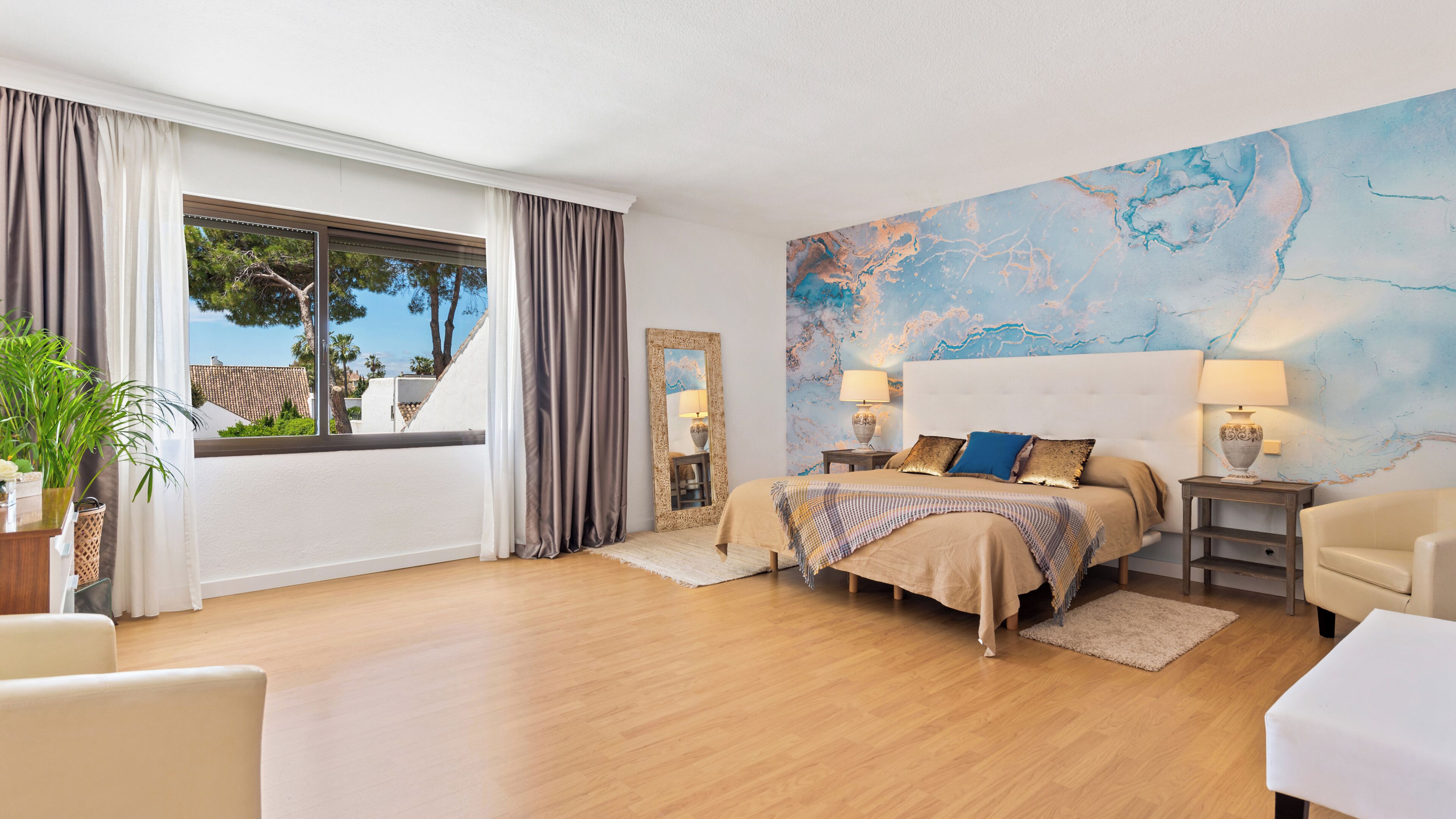 Un dormitorio amplio con una cama grande, vistas al exterior y un mural decorativo.