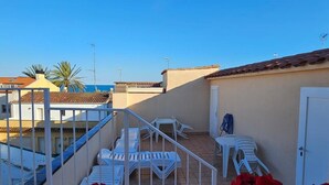 A rooftop terrace with white chairs and a small table, a door, and a view of the sea. - Hotel Blue Spot (Malgrat de Mar)