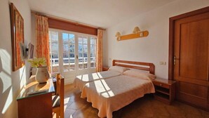 A bedroom with two beds, a desk, a chair, a bedside table, a lamp, and a wardrobe. - Hotel Blue Spot (Malgrat de Mar)