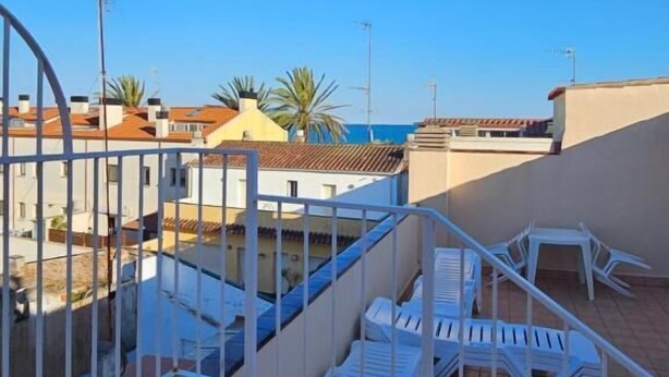 A rooftop terrace with white chairs and a railing, overlooking a residential area with houses and a clear blue sky. - Hotel Blue Spot (Malgrat de Mar)
