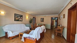 A room with a sofa, a dining table, and chairs. There are two paintings on the wall. - Hotel Blue Spot (Malgrat de Mar)