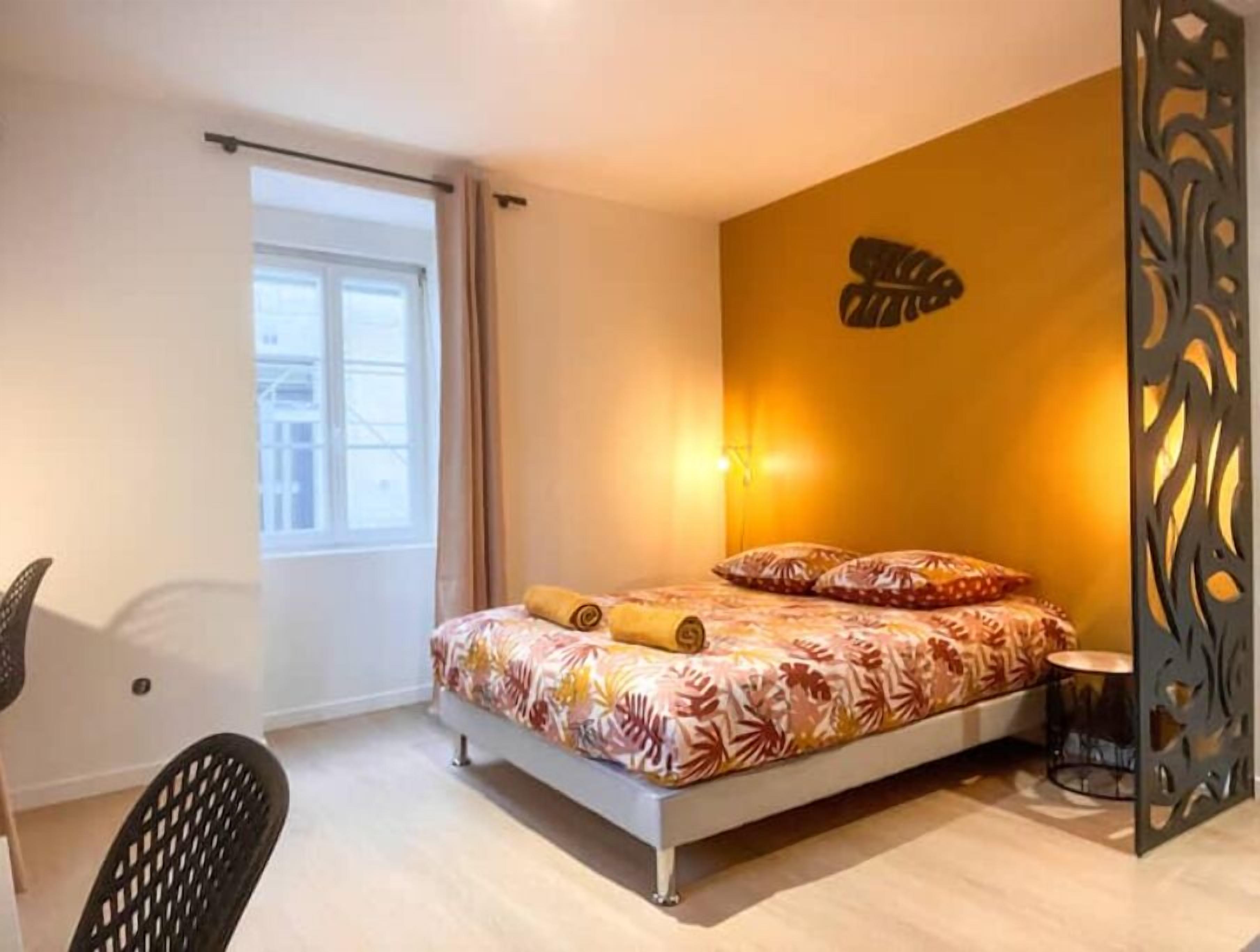 A bedroom with a bed, a chair, a window, and a decorative wall panel.