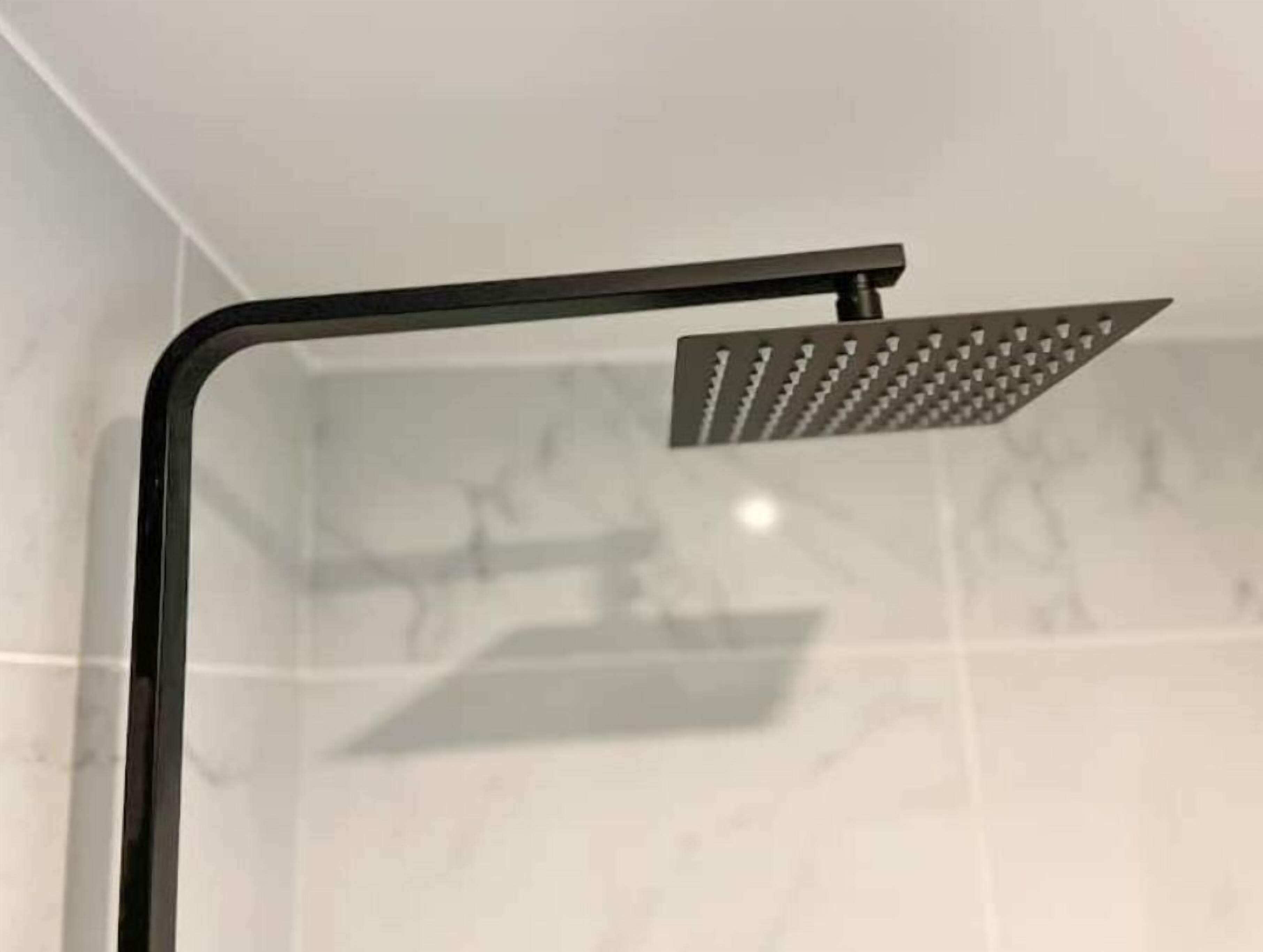 Een douche met een zwarte omlijsting en een vierkante douchekop.