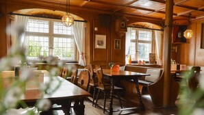 Un restaurante acogedor con muebles de madera, ventanas amplias y lámparas colgantes.