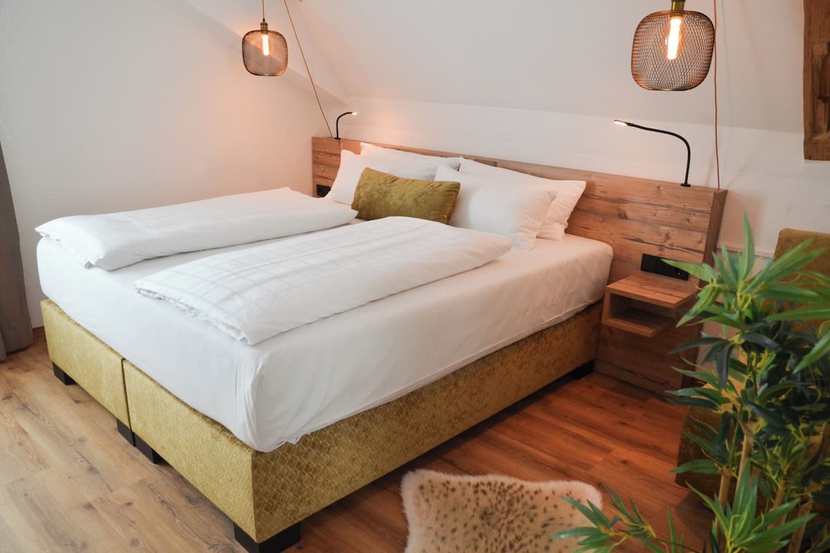 A neatly made bed with white linens, a wooden headboard, and two bedside tables with lamps.