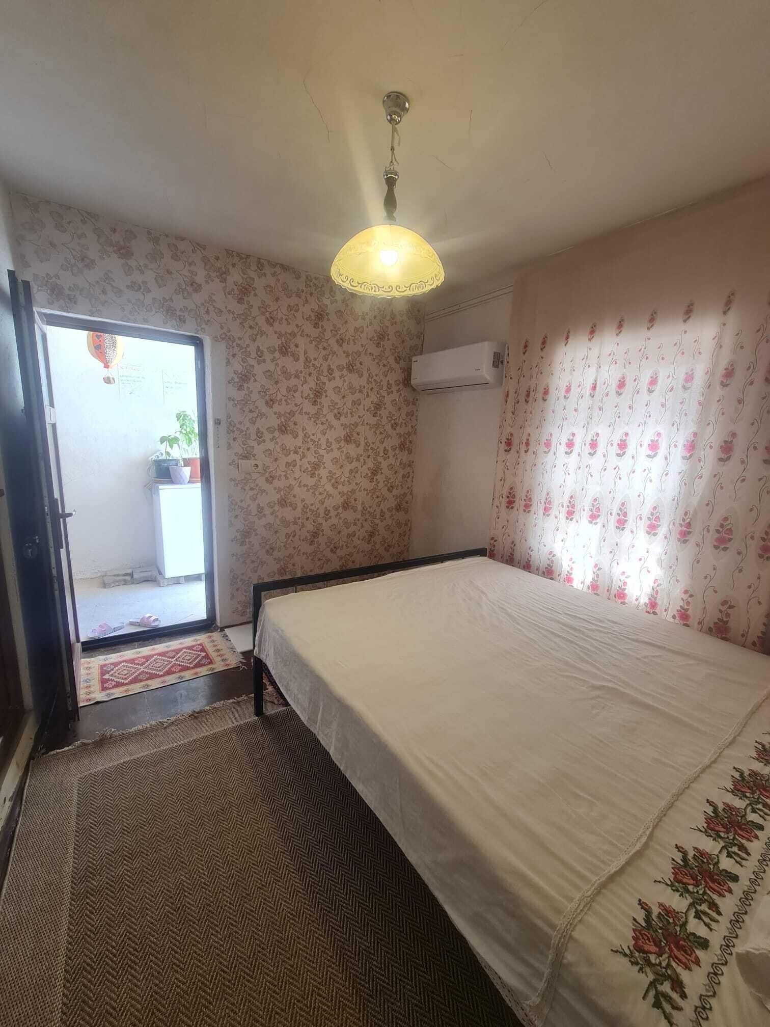 Ein Schlafzimmer mit Bett, Deckenventilator, Klimaanlage und einer Tür zum Balkon.