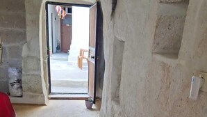 A narrow corridor with a wooden bench, green planters, and a doorway leading outside. - King Solomon Palace  (Avanos)