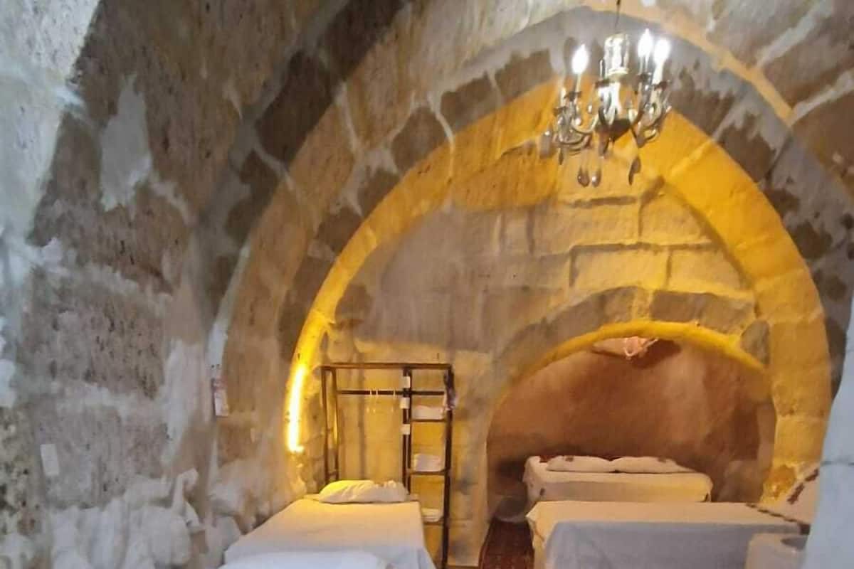Una habitación con dos camas, un colorido carpeta a rayas y un arco de piedra.