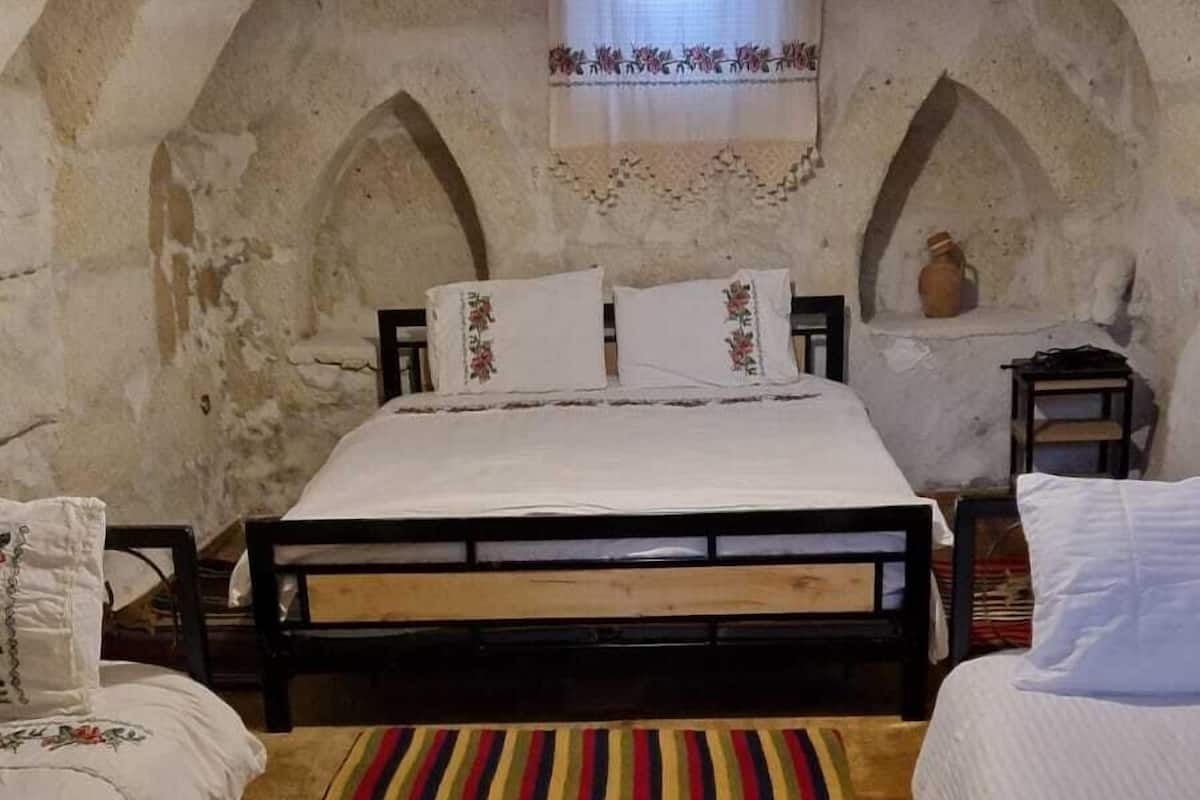 Una habitación con una cama, dos mesitas de noche, un colorido tapete a rayas y un techo abovedado.
