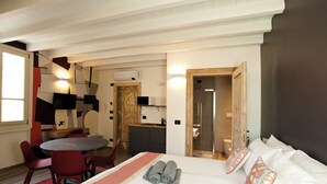 A hotel room with a bed, a desk, a chair, a small kitchen area, and a bathroom. - ANNAMA Coliving (Brescia)