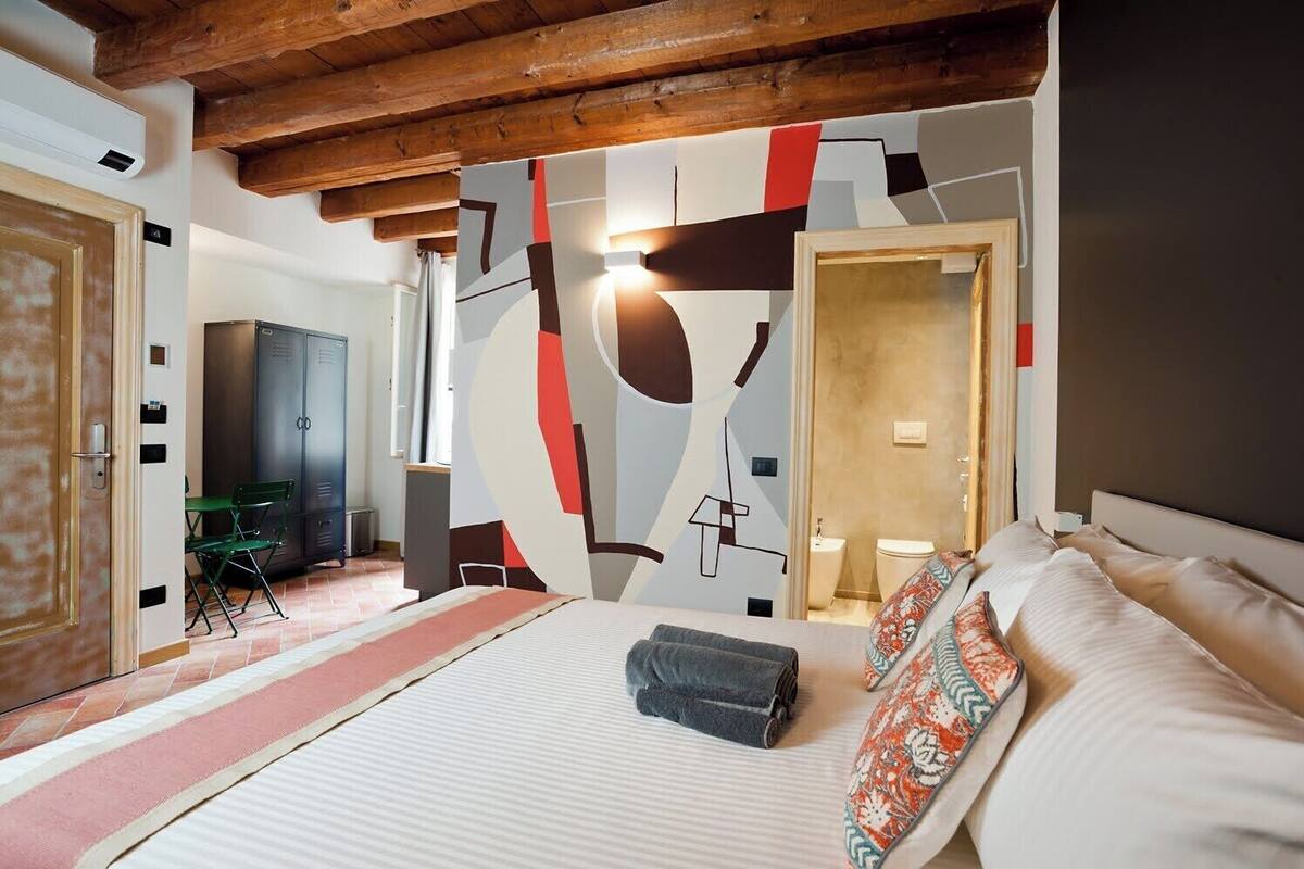 Quarto de hotel com cama, escrivaninha e guarda-roupa.