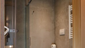 A modern bathroom with a glass shower enclosure, a white sink, and two toilets. - ANNAMA Coliving (Brescia)