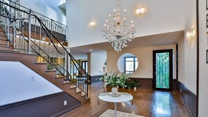 Ein geräumiges Foyer mit einer imposanten Treppe, einer Chandelier und einem runden Tisch mit Blumen.