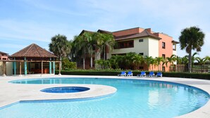 A swimming pool with blue water, surrounded by lounge chairs and palm trees. - Magic Arena Blanca Beach Suite (Punta Cana)