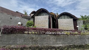 A modern house with a unique architectural design, featuring two curved roofs and a stone facade. - Belvilla Darshana Bali Zoo (Batubulan)