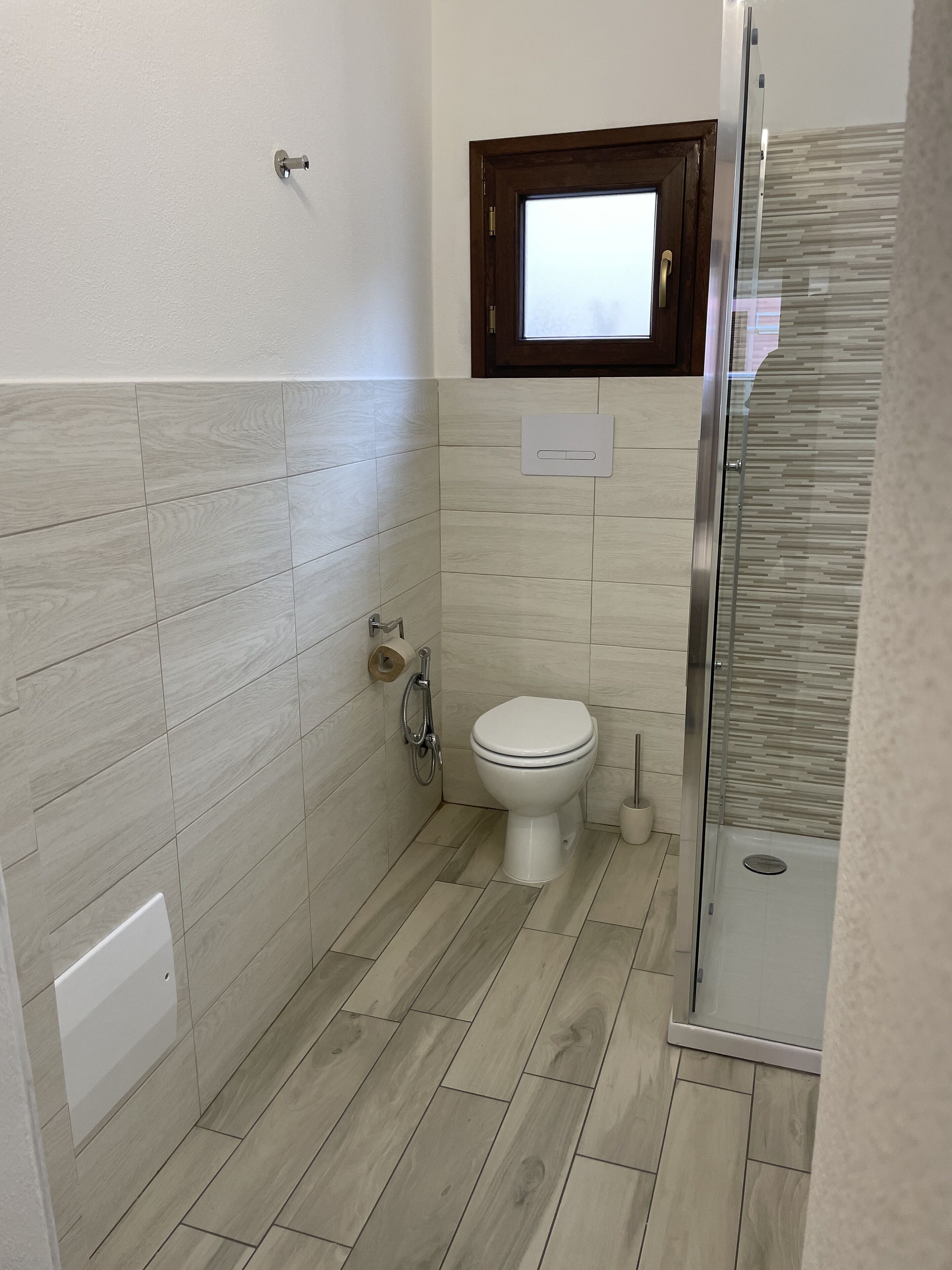 A bathroom with a toilet, a shower, and a window.