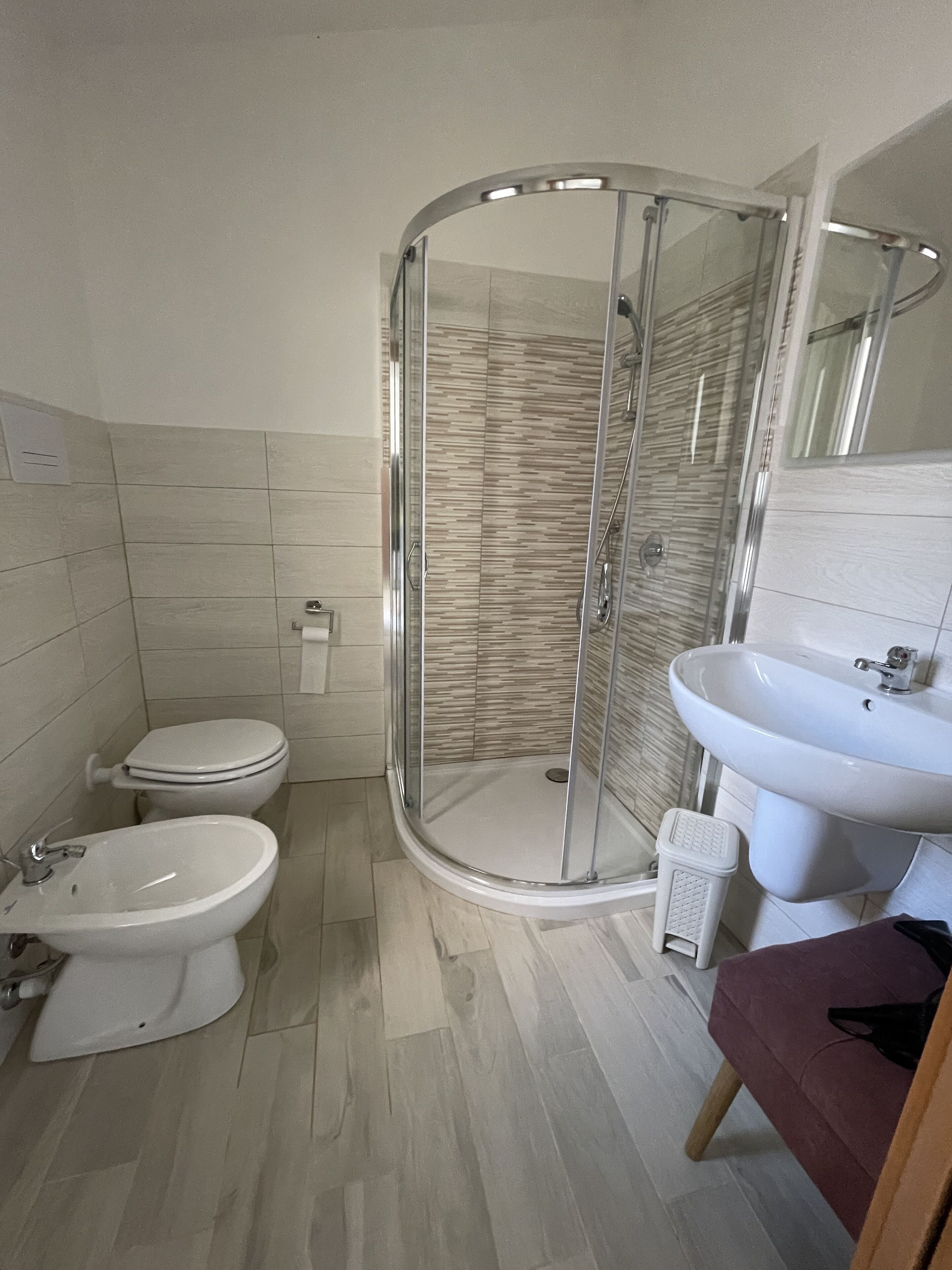 A bathroom with a glass-enclosed shower, a toilet, a bidet, and a sink.