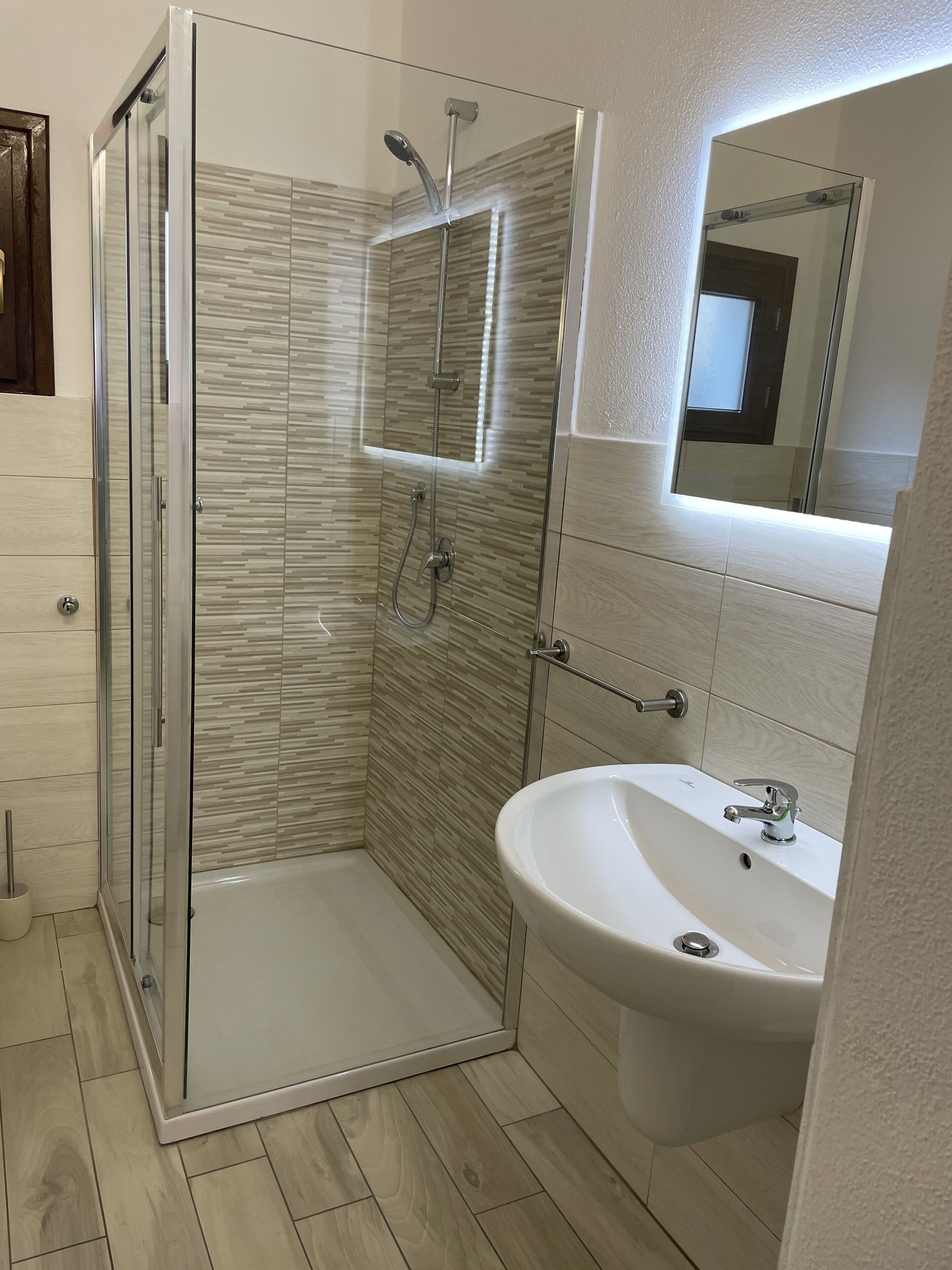 Une salle de bain moderne avec une douche à parois de verre, un lavabo et un miroir.