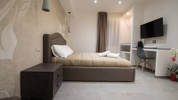 Une chambre d’hôtel moderne équipée d’un lit, d’un bureau, d’une télévision et d’une petite plante.