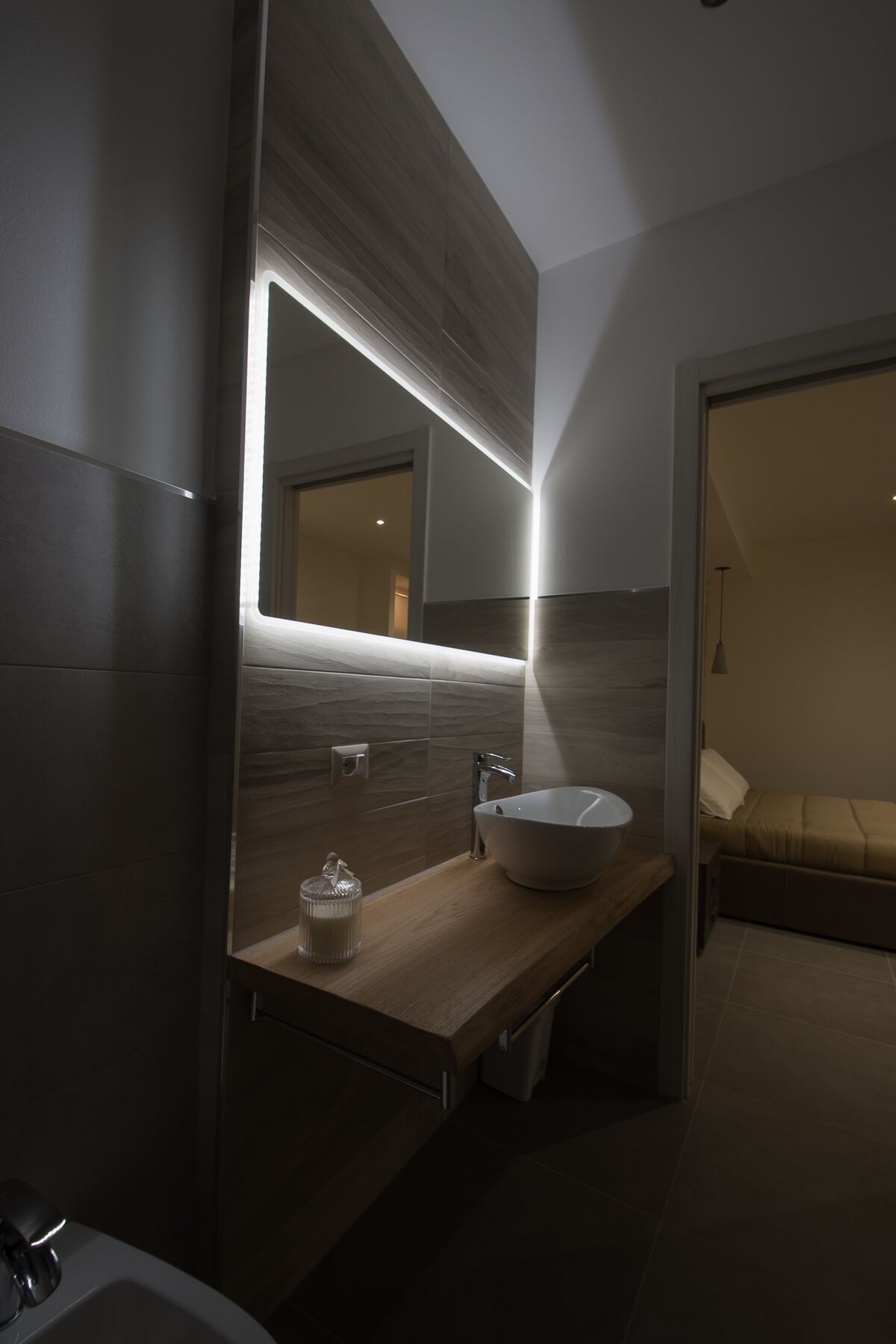 Ein modernes Badezimmer mit einem großen Spiegel, einem Haubenspültopf und einer Holzausziehtafel.
