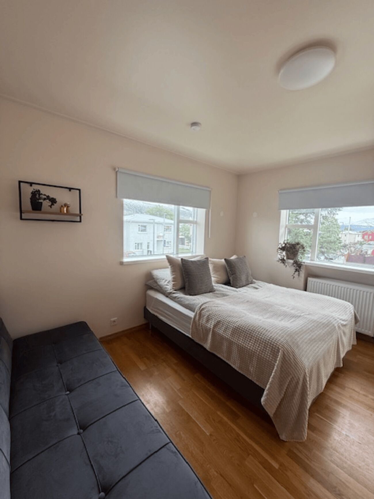 A bedroom with a bed, a bench, and two windows.