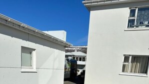 A narrow alleyway between two white buildings with a paved ground. - Nordurgata 43 (Akureyri)