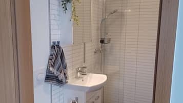 A modern bathroom with a white toilet, a sink, and a shower.