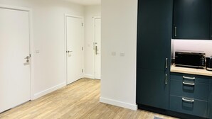 A modern kitchen with dark cabinets, a microwave, and a wooden floor. - Your London Escape Luxurious 1 Bedroom Apartment (Wembley)