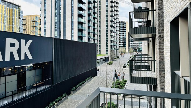 A modern urban building with a prominent 'ARK' sign, multiple balconies, and a pedestrian walkway. - Your London Escape Luxurious 1 Bedroom Apartment (Wembley)