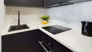 A kitchen with a black sink, a black stovetop, and a black dishwasher. - Modern Studio with Workspace | Close to Metro (Warszawa)