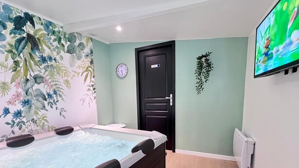 Quarto com hidromassagem, relógio, porta e televisão na parede.