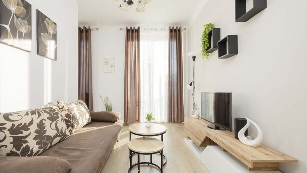 A modern living room with a sofa, a coffee table, a TV, and a bookshelf.