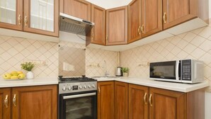 A kitchen with wooden cabinets, a stove, an oven, a microwave, and a tiled backsplash.