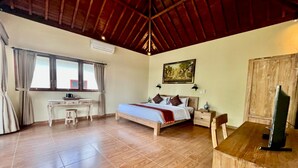 A bedroom with a wooden bed, a desk, and a TV. - Belvilla Chaitanya Niketan (Ubud)