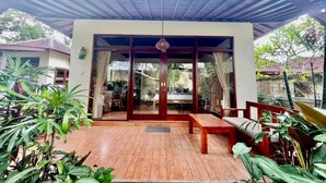 A covered patio with wooden flooring, a bench, and potted plants. - Belvilla Chaitanya Niketan (Ubud)