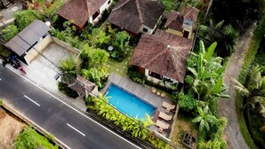 A residential area with multiple houses, a swimming pool, and a road. - Belvilla Chaitanya Niketan (Ubud)