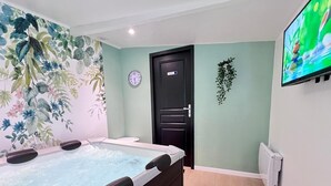 Ein Zimmer mit Whirlpool, einer Uhr, einer Tür und einem Fernseher an der Wand.