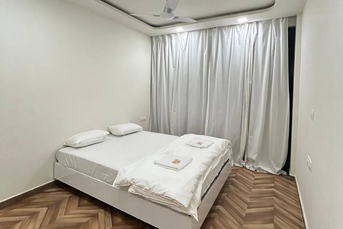 A bedroom with a bed, a ceiling fan, and a window with curtains.