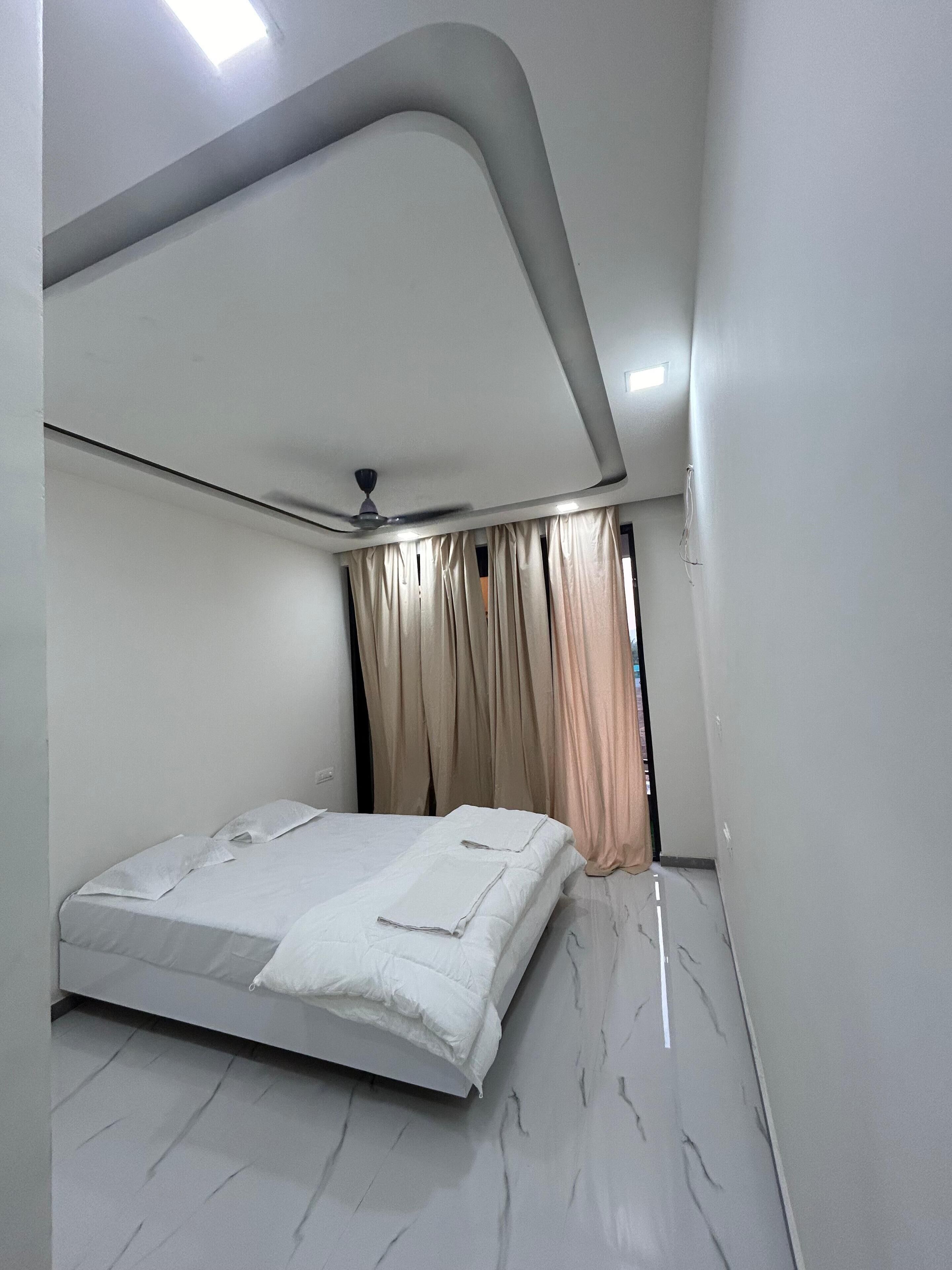 A modern bedroom with a bed, curtains, and a ceiling fan.