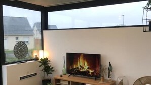A modern living room with a fireplace, a television, and a view of the outside. - ''dolmen'' (Plobannalec-Lesconil)