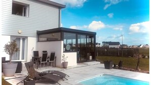 A modern house with a swimming pool, outdoor seating, and a glass-enclosed patio. - ''dolmen'' (Plobannalec-Lesconil)