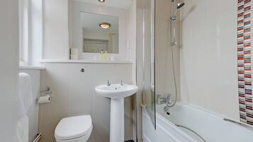 A bathroom with a toilet, sink, and shower.