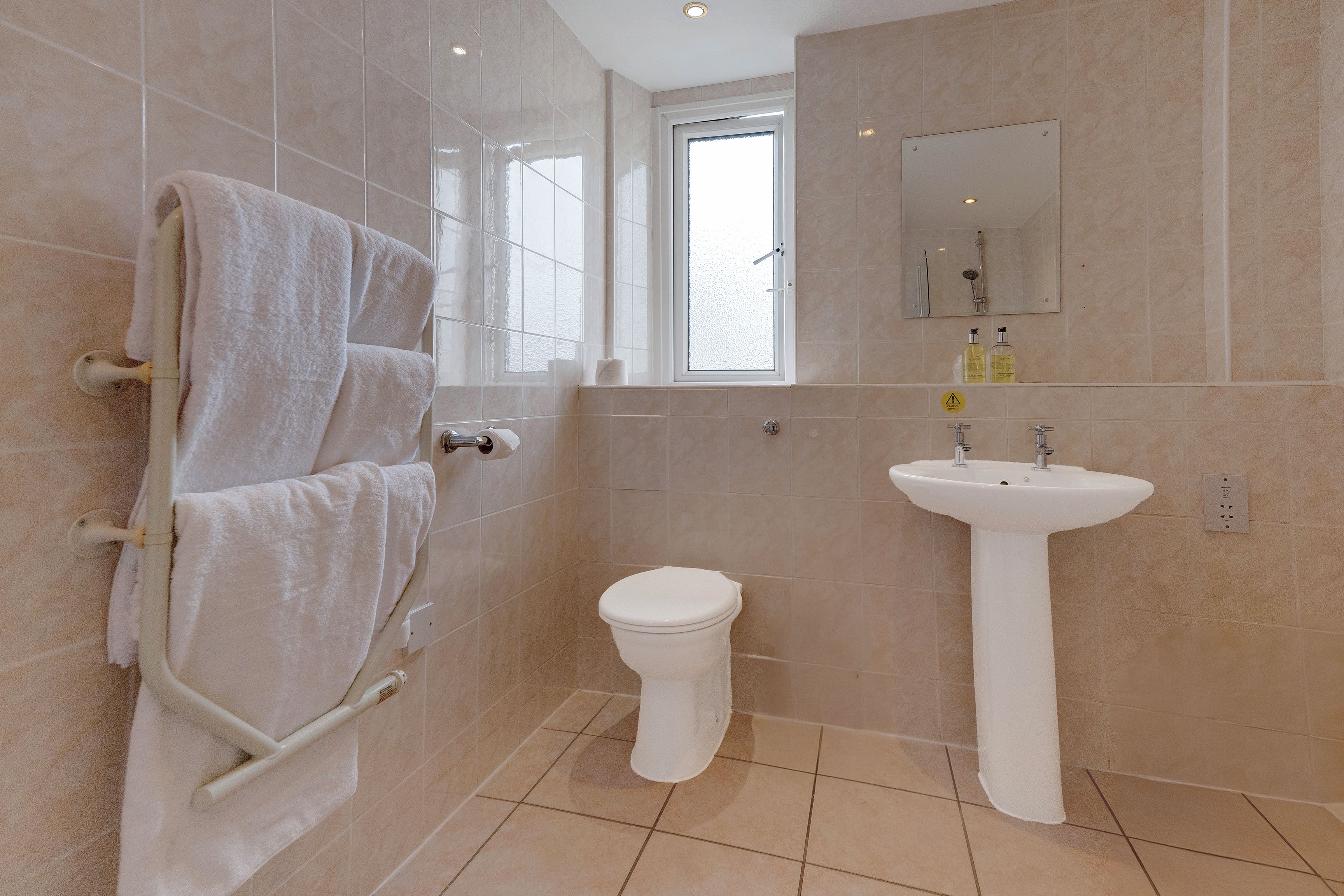 A bathroom with a toilet, sink, and towel rack.