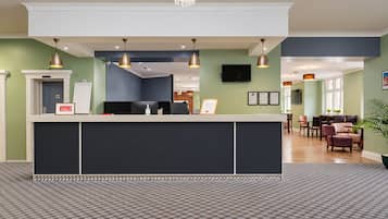 A reception area with a counter, a television mounted on the wall, and a seating area with chairs and a table.