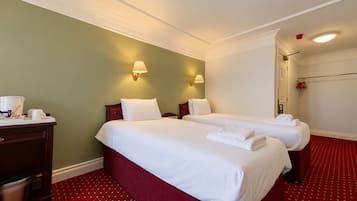 A hotel room with two beds, a desk, and a red carpet.