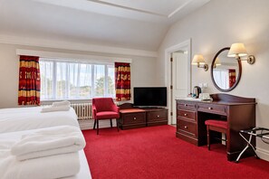 A hotel room with a bed, a desk with a chair, a television, a mirror, and a red carpet. - Belvilla Crewe Arms Hotel (Crewe)