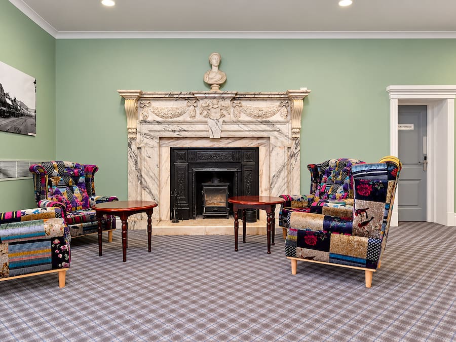 A room with a fireplace, two armchairs, a small table, and a door labeled 'Albert Room'.