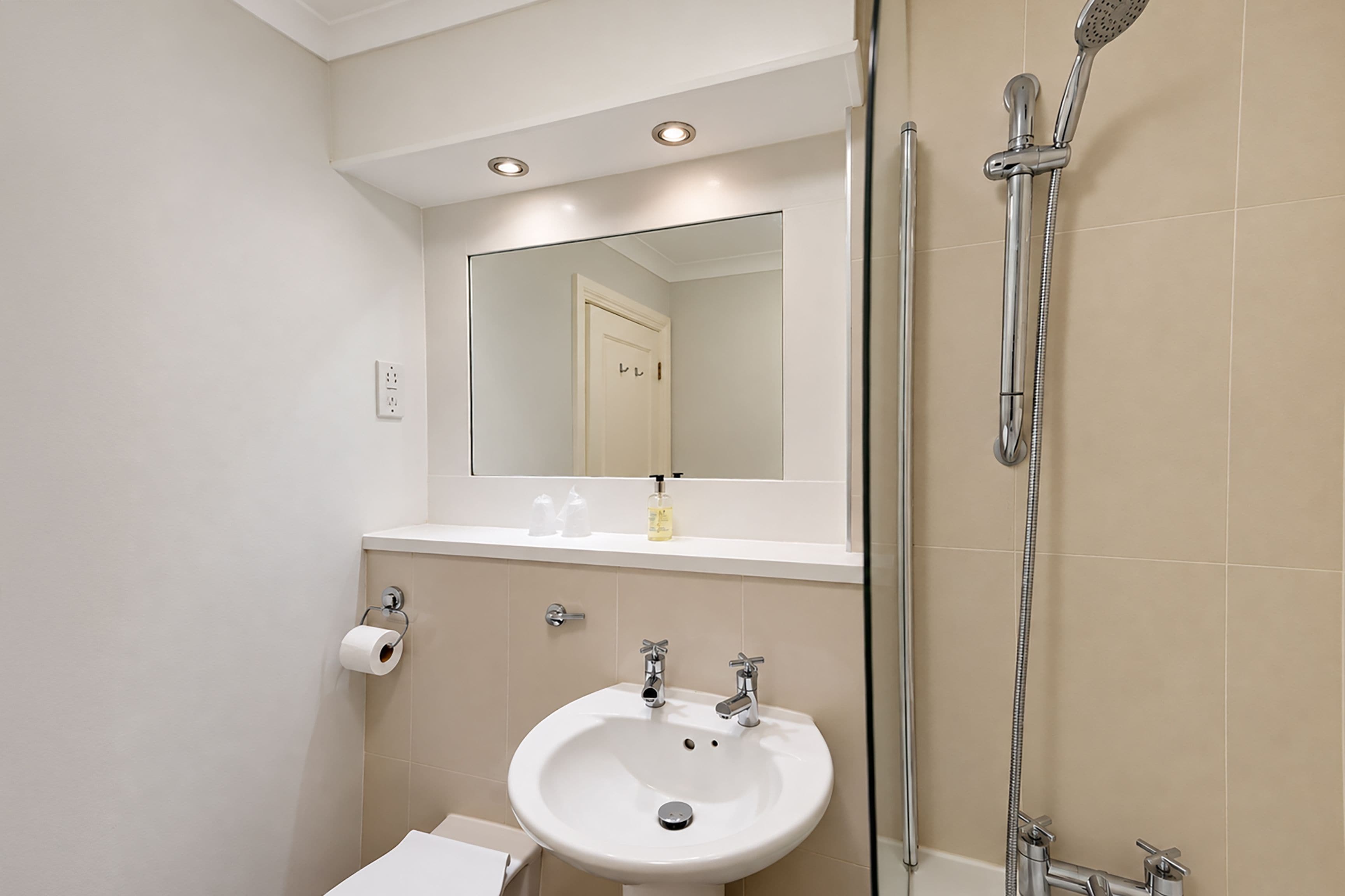 A bathroom with a white sink, a mirror, and a shower.