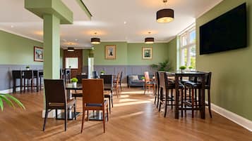 A spacious dining area with a high ceiling, wooden flooring, and modern furniture.